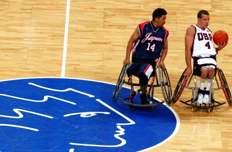Josh Turek, right, controls the ball as Japan's Tomohiko Oshima tries to stop him during a wheelchair basketball match at the Athens 2004 Paralympic Games.