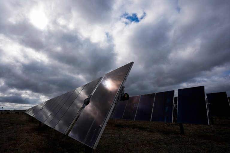 The sun reflects off of a solar panel on a solar farm owned by SB Energy