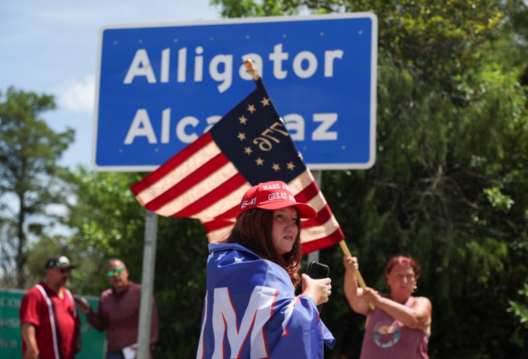 Dianne Mourer waves an American flag as Rana Mourer stands in front of a sign reading 