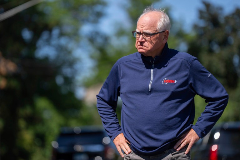 Gov. Tim Walz (D-MN) stands outside with his hands on his hips.