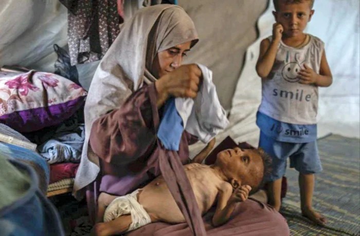 Mohammad al Motawaq with his mother and, right, brother, in one of several photographs of the 18-month-old released by Hamas in late July to reinforce claims that children in Gaza were starving. It later emerged that Mohammad was born with cerebral palsy.