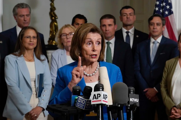 Nancy Pelosi speaks into a variety of microphones