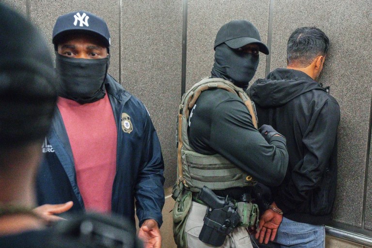 Immigration and Customs Enforcement agents escort a detained immigrant into an elevator.