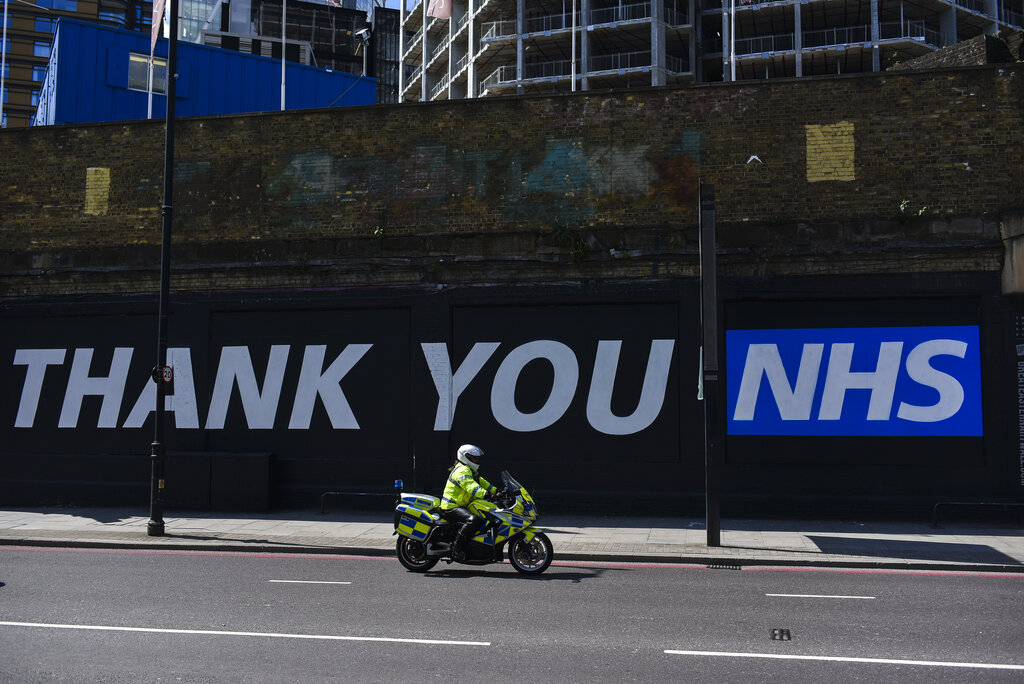 A Police Officer rides past a mural with a message saying 'Thank you NHS' (National Health Service), in London, Tuesday, May 12, 2020. (AP Photo/Alberto Pezzali)