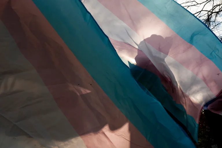 A protester is silhouetted against a trans pride flag during a pro-transgender rights protest outside of Seattle Children's Hospital, Feb. 9, 2025, in Seattle.