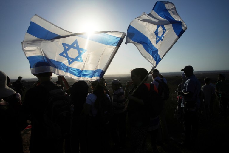 Israeli right-wing activists carry national flags during a rally calling for the re-establishment of Jewish settlements in the Gaza Strip, near the border in southern Israel, Wednesday, July 30, 2025. (AP Photo/Ohad Zwigenberg)
