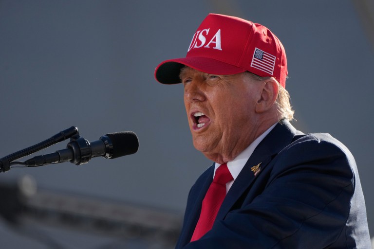 President Donald Trump speaks into a microphone.