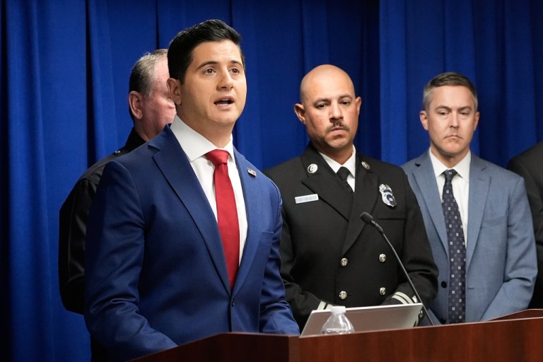 Acting U.S. Attorney Bill Essayli, foreground, speaks during a news conference.