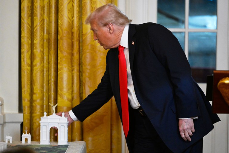 President Donald Trump touches a miniature model at a donor dinner.