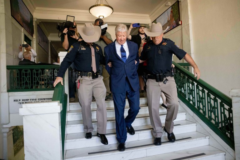 Robert Morris is escorted down stairs by two police officers