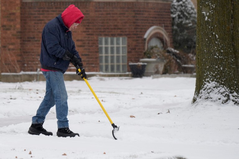 A man cleans snow in front of his home.