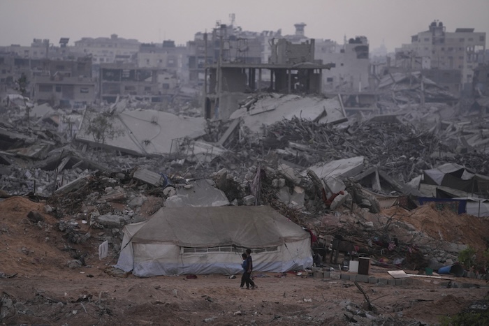 Palestinians walk through the destruction caused by the Israeli air and ground offensive in Sheikh Radwan neighborhood in Gaza City, Monday, Nov. 10, 2025. (AP Photo/Jehad Alshrafi)