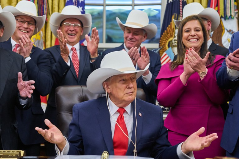 President Donald Trump tries on a hat gifted to him from members of the 1980 U.S. Men's Olympic Hockey team Friday, Dec. 12, 2025, in the Oval Office of the White House in Washington. (AP Photo/Jacquelyn Martin)