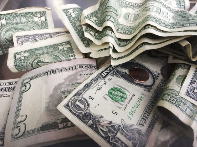 A tip jar of one dollar and five dollar bills.