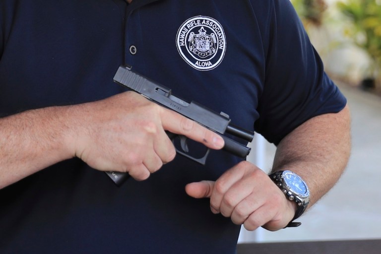 Kainoa Kaku, president of the Hawaii Rifle Association, checks one of his personal firearms.