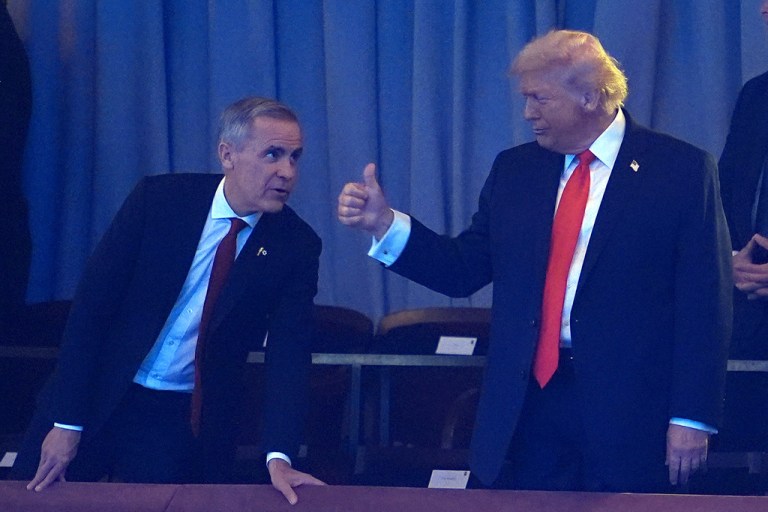 Canadian Prime Minister Mark Carney, left, leans over to President Donald Trump as they take their seats at the Kennedy Center for the 2026 FIFA World Cup draw