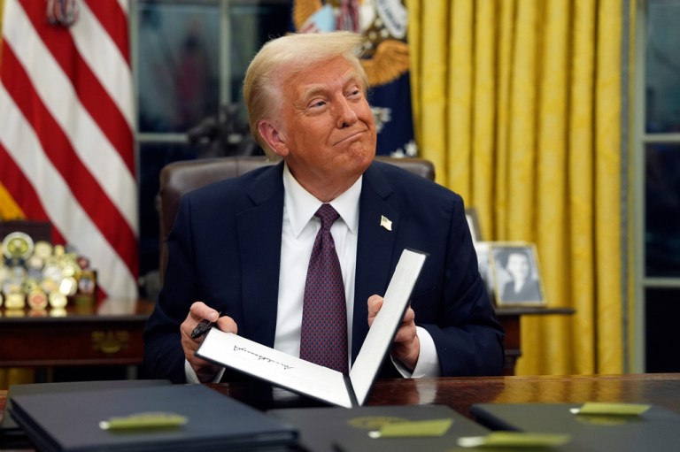President Donald Trump signs executive orders in the Oval Office of the White House.