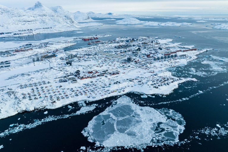 An aerial view of houses covered by snow on the coast of a sea inlet in Nuuk, Greenland.