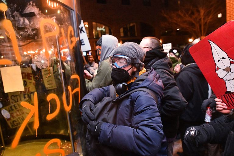 Anti-ICE demonstrators protest outside the graffiti tagged Graduate Hotel where federal immigration agents are believed to be staying in Minneapolis on Jan. 13, 2026. Hundreds more federal agents were heading to Minneapolis, the US homeland security chief said on January 11, brushing aside demands by the Midwestern city's Democratic leaders to leave after an immigration officer fatally shot a woman protester. In multiple TV interviews, US Homeland Secretary Kristi Noem defended the actions of the officer who shot and killed 37-year-old Renee Nicole Good, whose death has sparked renewed protests nationwide against President Donald Trump's immigration crackdown. (Photo by Octavio JONES / AFP via Getty Images)