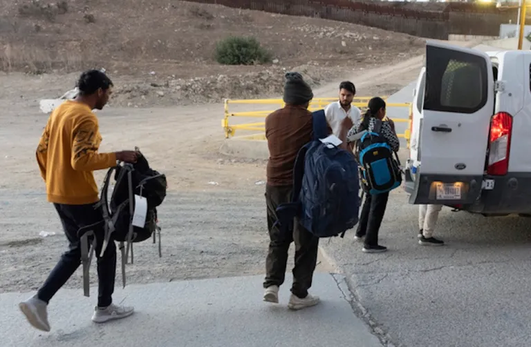 Migrants make their way to a Border Patrol van.