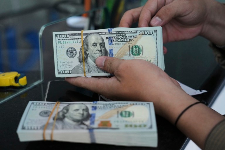 An employee counts U.S. dollar notes at a money changer in Jakarta, Indonesia, Thursday, Aug. 7, 2025. (AP Photo/Tatan Syuflana)