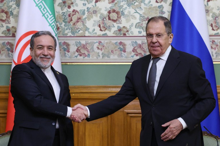 Russian Foreign Minister Sergey Lavrov and Iranian Foreign Minister Abbas Araghchi shake hands.