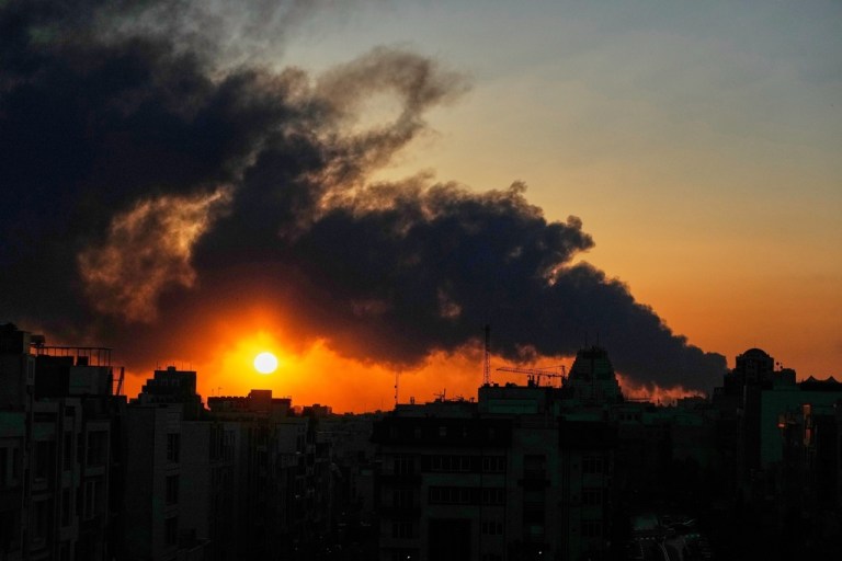 The sun sets behind a plume of smoke rising from a U.S.–Israeli military strike in Tehran, Iran, Tuesday, March 3, 2026. (AP Photo/Vahid Salemi)