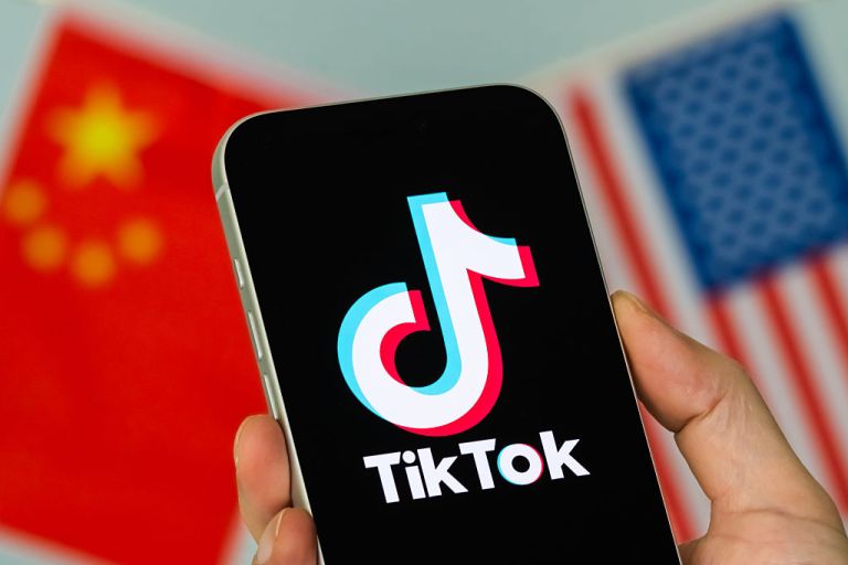 TikTok logo on a phone with Chinese and American flags in the background.