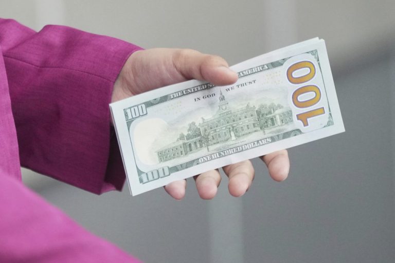 An employee holds dollars banknotes at a money changer in Jakarta.