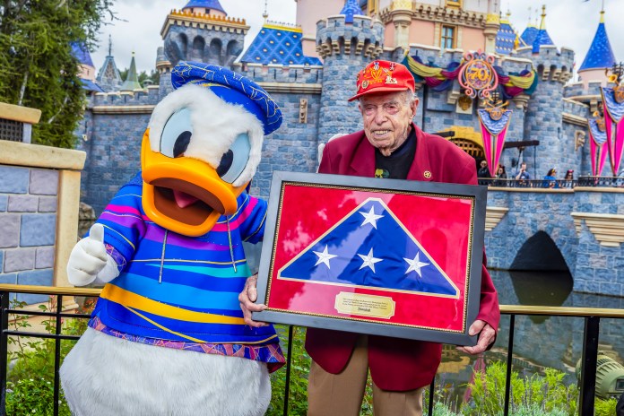 Anaheim, Calif. (March 31, 2026) - Donald Duck greets 100- year-old World War II veteran Charles Cram during a special meet and greet in the Castle Gardens. Donald Duck is a beloved Disney character popular with the U.S. Armed Forces, as he helped boost patriotic storytelling throughout World War II.