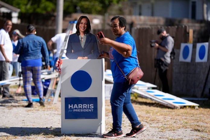 Arlett Brooks, of Omaha, Neb., takes a selfie with a cutout of Democratic presidential nominee Vice President Kamala Harris during a blue dot campaign sign get-together, Tuesday, Sept. 24, 2024, in Omaha, Neb. The blue dot signs, spotted throughout Omaha, represent Democratic-voting households in a state surrounded by Republican red