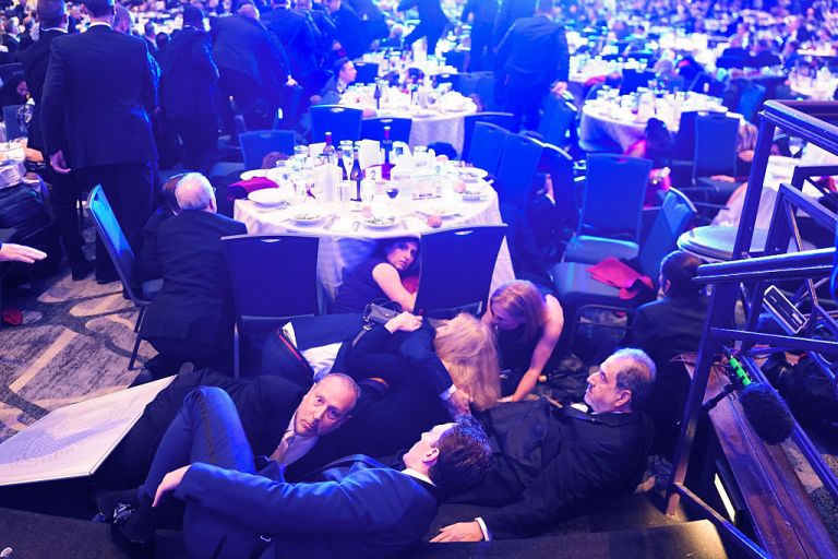 Guests take cover at the White House Correspondents' Association dinner on April 25, 2026.