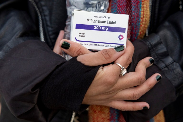 An abortion-rights activist holds a box of mifepristone pills.
