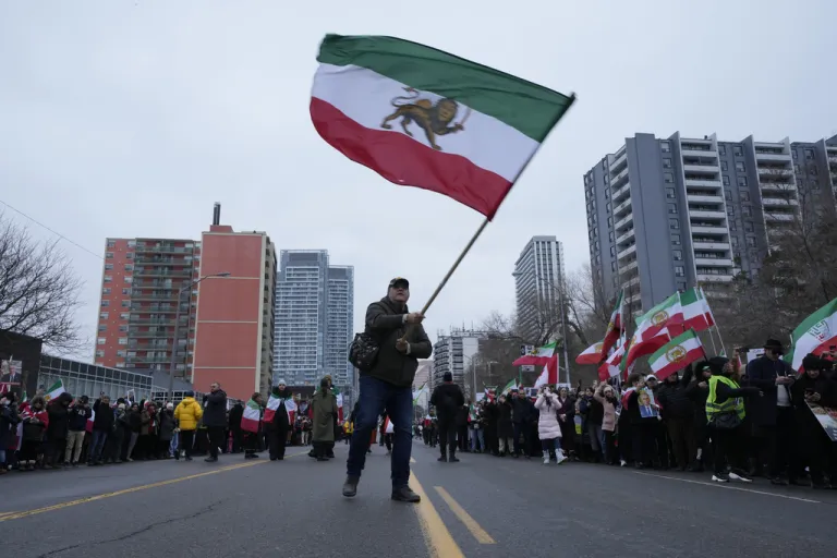 A man waves the lion and sun flag during a demonstration of Iran's exiled Crown Prince Reza Pahlavi in Toronto, Saturday, Feb. 14, 2026.