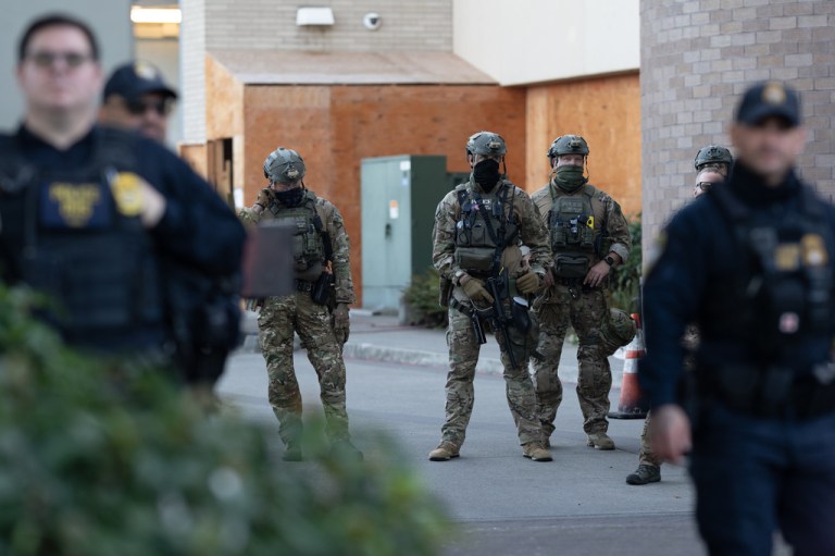 Law enforcement officers look out from an ICE facility