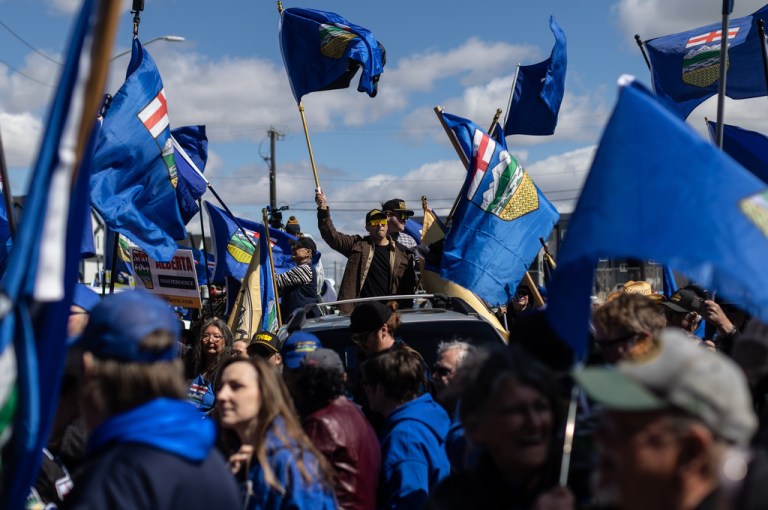 Supporters fly flags in support of Mitch Sylvestre as he submits his signatures for a separation referendum to Elections Alberta in Edmonton, on Monday, May 4, 2026.