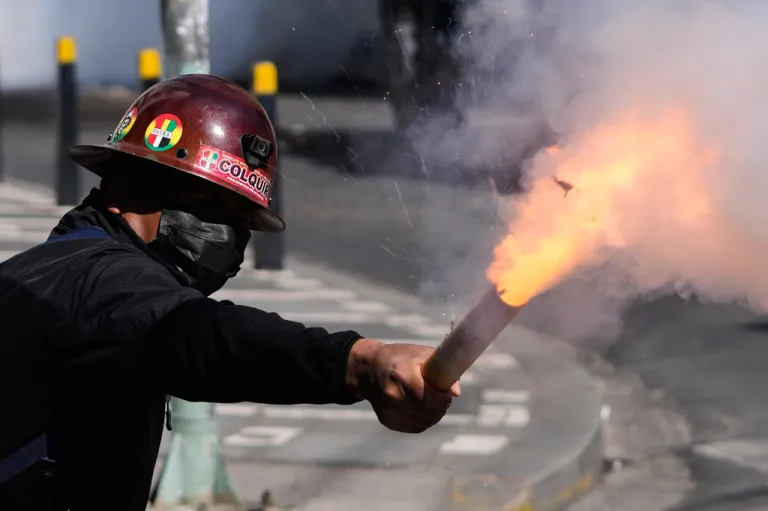 A miner launches a firecracker at police during an anti-government protest.