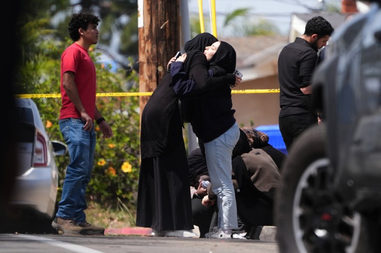 People embrace near the scene of a shooting outside the Islamic Center of San Diego