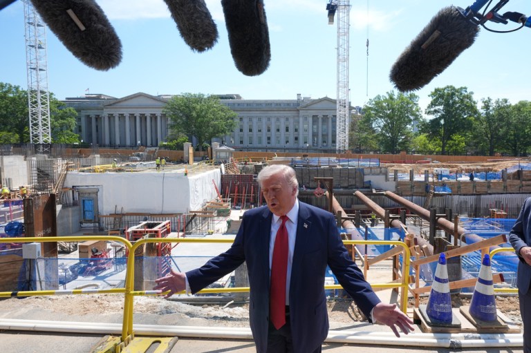 President Donald Trump speaks as he tours ballroom construction around the outside the White House.