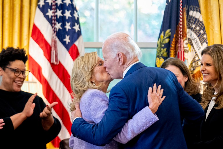 President Joe Biden, accompanied by Office of Management and Budget director Shalanda Young, left, and Women's Alzheimer's Movement founder Maria Shriver, right, gives first lady Jill Biden a kiss after giving her the pen he used to sign a presidential memorandum that will establish the first-ever White House Initiative on Women's Health Research in the Oval Office.