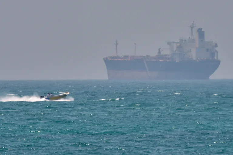 A boat sails past a tanker anchored on the Strait of Hormuz off the coast Qeshm island