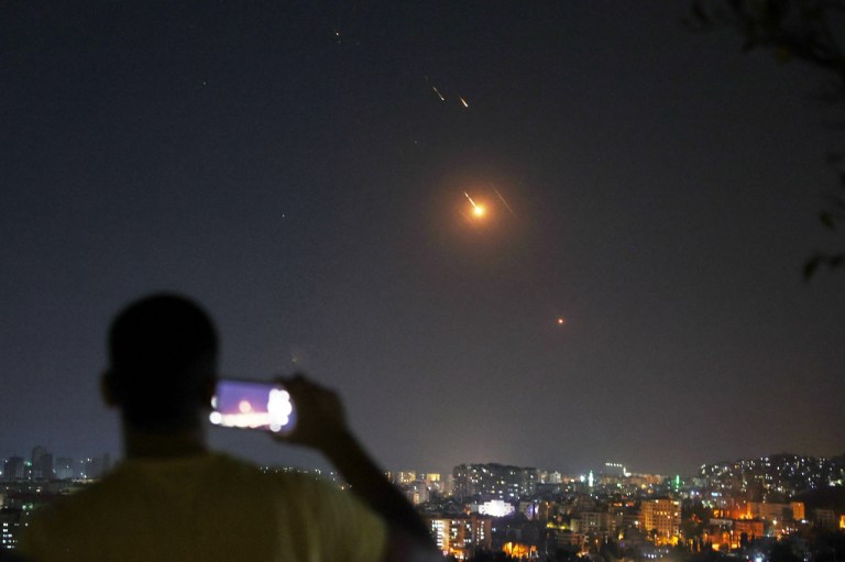 A man takes a cellphone photo as missiles fired from Iran toward Israel fly overSyrian territory in Damascus, Syria, early Wednesday, June 18, 2025.