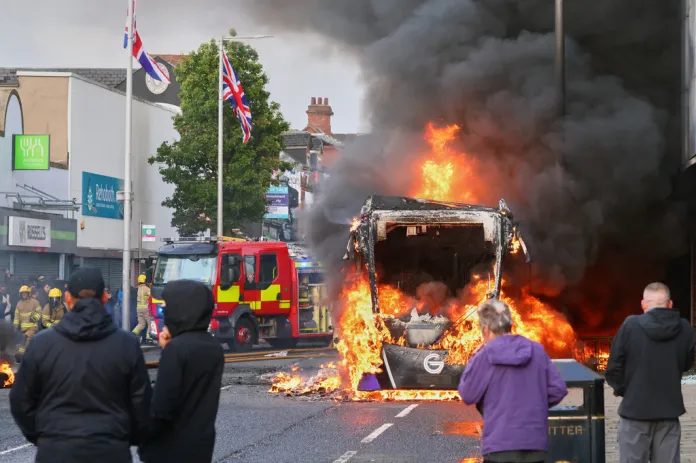 People watch as a vehicle burns during a protest in East Belfast.