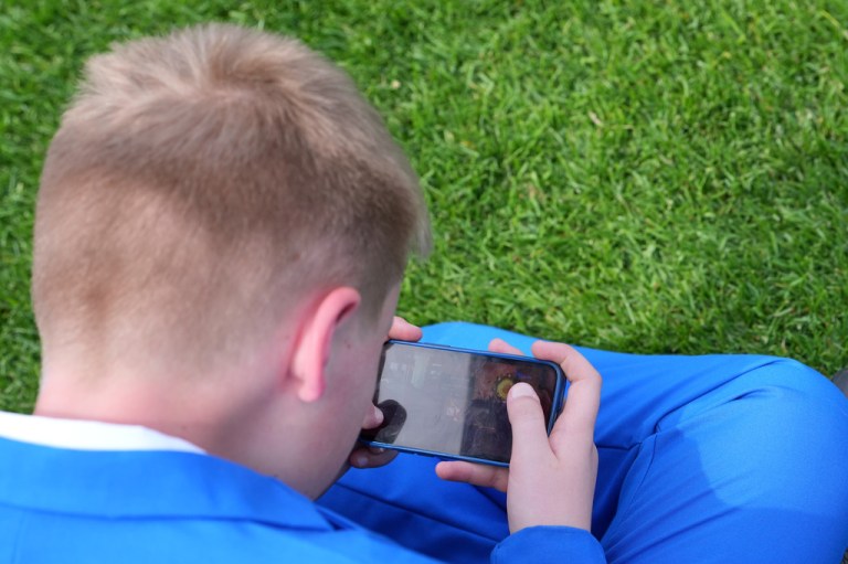 A young boy plays on his mobile phone.